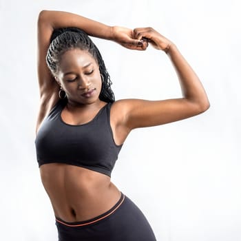 Close up of muscular african teen girl doing stretching exercise.Young woman in sportswear  hips isolated on white background.