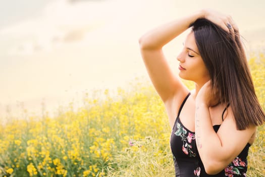 Close up portrait of attractive woman relaxing with eyes closed in yellow flower field.