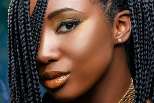 Extreme close up facial beauty portrait of  young charming african girl with braided hairstyle.Studio shot of woman with professional make up looking at camera.