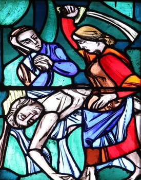Judith, liberator of her people, kills the enemy captain Holofernes, Stained glass window in Basilica of St. Vitus in Ellwangen, Germany