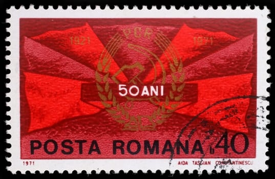 Stamp printed in Romania shows Red flags and communist party badge, 50 years P.C.R., circa 1971.