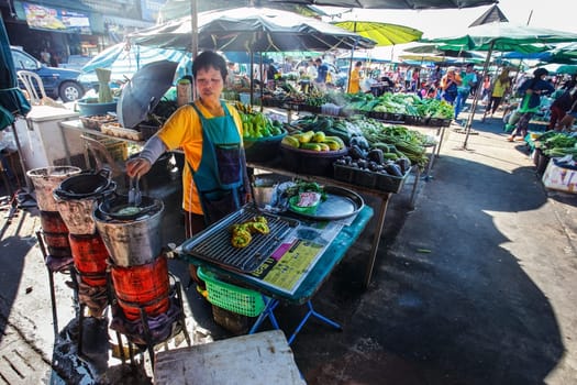 Khao Lak, Thailand - February 22, 2016: Local woman preparing vegetable latkes in her mobile stall in morning market. Thai cuisine is renowned for its tasty food.