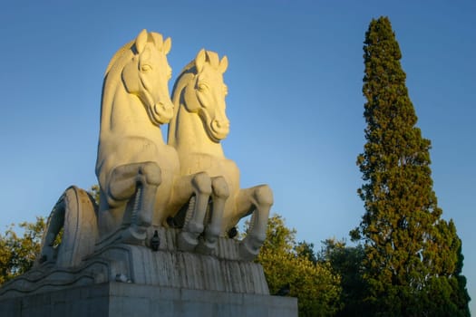 Lisbon, Portugal - September 17, 2006: Statute of two sea horses (mythological hippocampi ) in Empire Square park (Praca do Imperio) lit by evening sun.