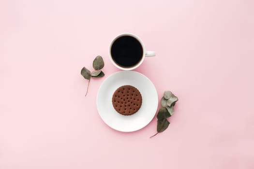 Woman international day concept, coffee cup, plate, cookie, branch, eucalyptus leaves on pink background. High quality photo