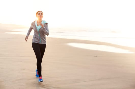 Beautiful and healthy woman running on the beach
