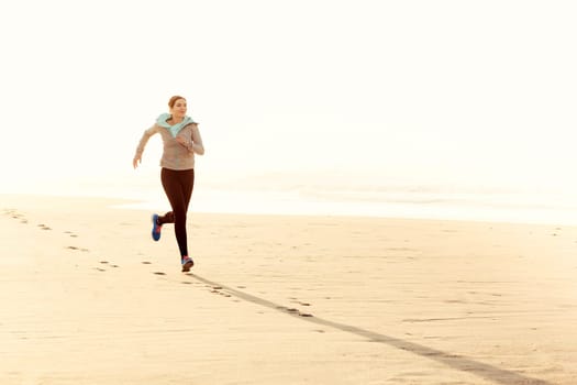 Beautiful and healthy woman running on the beach