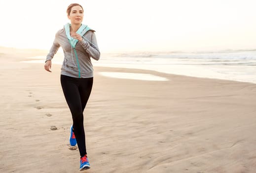 Beautiful and healthy woman running on the beach