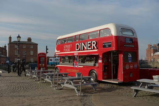 Liverpool, United Kingdom, 2nd February, 2020: Spring time sunshine lights the big red double decker street food diner bus found at the albert dock.
