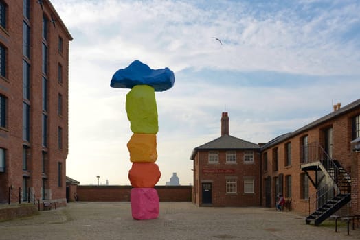 Liverpool, United Kingdom, 2nd February, 2020: Red brick buildings at the royal albert dock surround the liverpool mountain sculpture outside tate