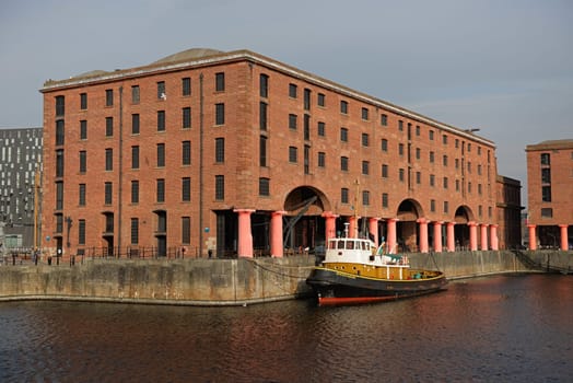 Liverpool, United Kingdom, 2nd February, 2020: Old brocklebank boat moored outside royal albert dock buildings on a sunny spring day, calm water.