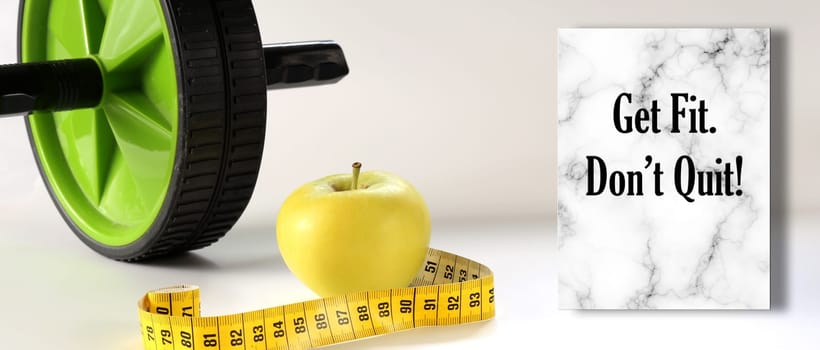 Healthy lifestyle motivational quote. Diet fitness and Healthy life Concept. Motivational Quote text Get Fit. Don't Quit. Apple, measure tape, sport home gym equipment ab roller for diet slimming