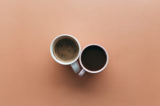 Two pink and blue coffee cups on beige background. High quality photo