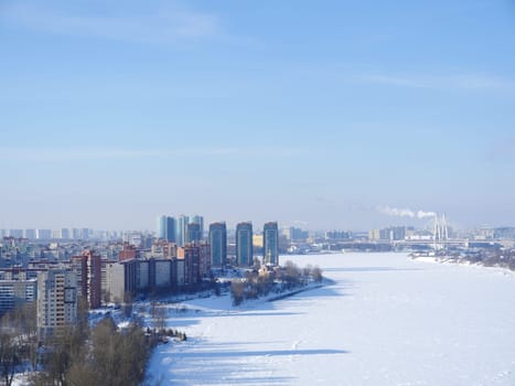 skyscrapers on the banks of the river white from snow, in the distance on the horizon a big city top view