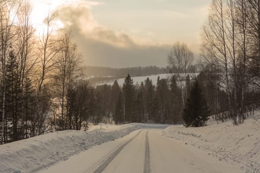 Empty snow covered road in winter landscape