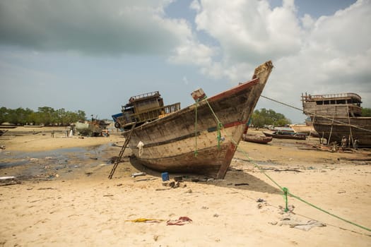 An old fishing boat is being repaired in the harbor by several workers.