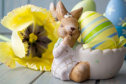Easter background yellow tulips on wooden table, Rabbit with eggs close up