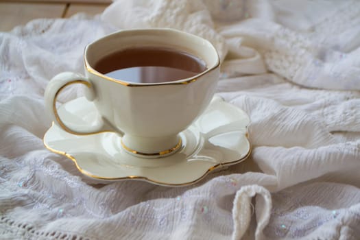 Antique porcelain tea cup full of tea on white vintage background close up