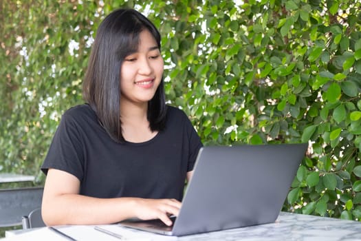 Young Asian woman freelance is working with laptop at coffee shop. Business woman typing, searching and checking document in modern cafe.  Working online technology system concept.