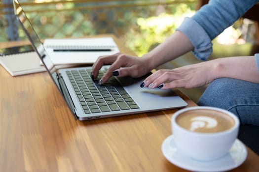 Close up female hands of a business freelance using laptop computer, searching in cafe. Working online technology system concept.