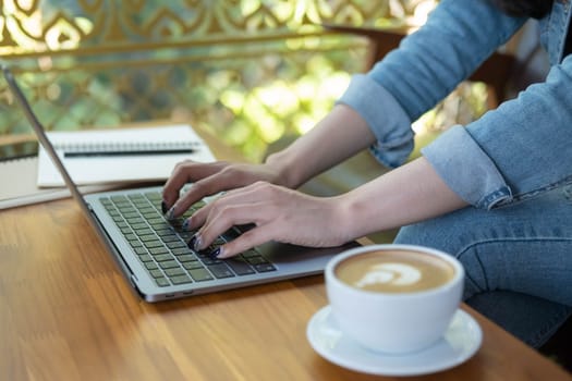 Close up female hands of a business freelance using laptop computer, searching in cafe. Working online technology system concept.