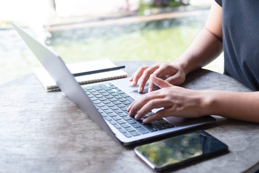 Close up female hands of a business freelance using laptop computer, searching in cafe. Working online technology system concept.