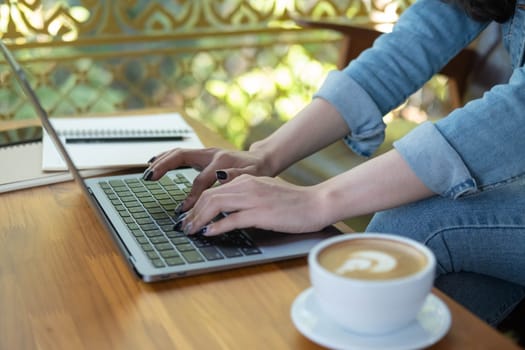 Close up female hands of a business freelance using laptop computer, searching in cafe. Working online technology system concept.