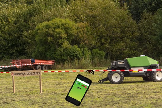 Autonomous tractor in the field. Wooden sign with inscription in German autonomous tractor. Smart farming and digital transformation in agriculture.