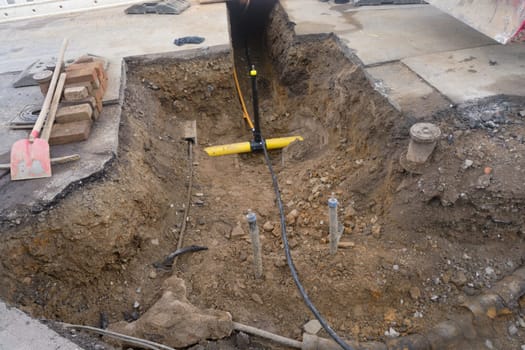 Work on the installation of engineering and heating systems. Two plastic pipes one yellow for gas pipe and one black for power lines. They are in a sand ditch.