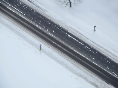 winter road is empty among white snow diagonally from above