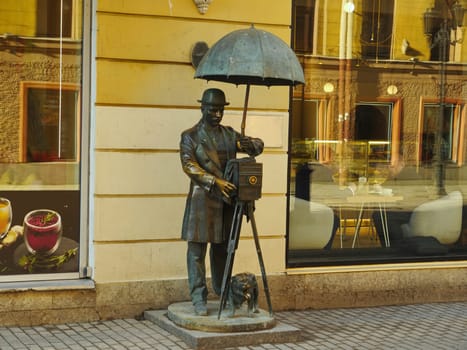 St. Petersburg, Russia, March 1, 2021. monument to mister photographer with old vintage camera umbrella and dog, symbol of a bygone time