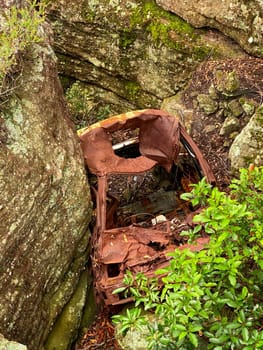 An old, rusted car down a cliff