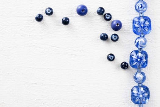 Blue and white glass beads,  on white painted wooden surface, top down view