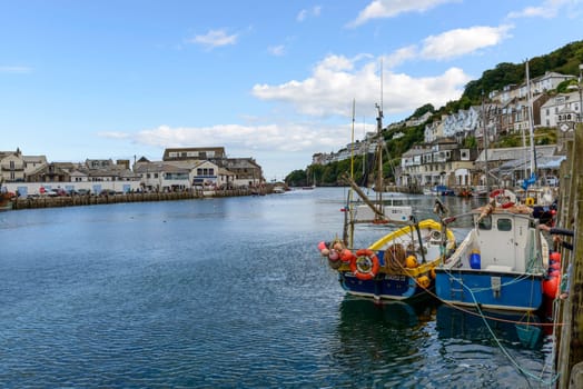 view of the river in small touristic village on Cornwall southern coast with two fishboats moored.