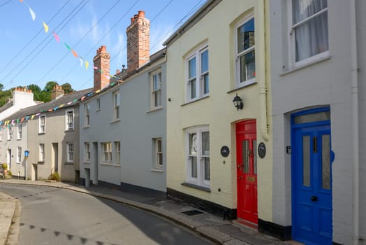 view of bending street with old houses in the village on southern coast of Cornwall.