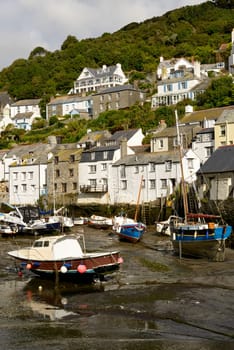 cityscape of the touristic village on southern coast of Cornwall with low tide in the river harbour and boats aground.