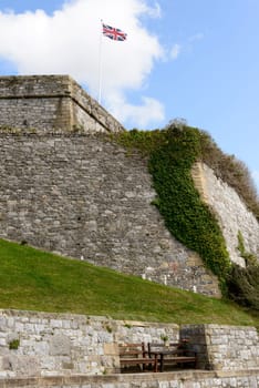 view of the huge wall that encloses the area of the castle with wooden benches and a waving Union Jack flag.