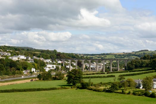 landscape of lush countryside with tall bridge crossing the river valley.
