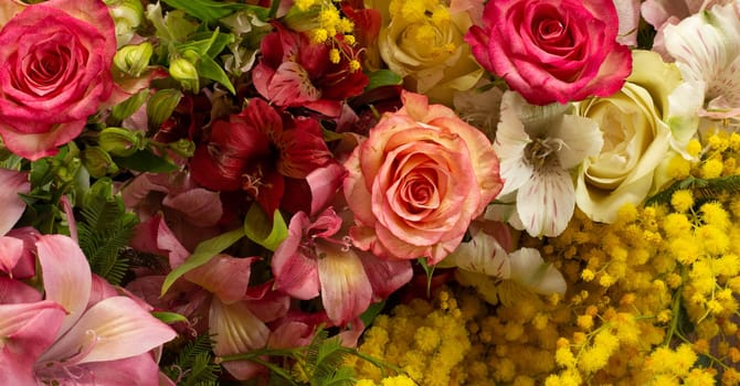 Flowers border composition in bright yellow red colours. Alstroemeria, roses, mimosa flowers. Flat lay top view, copy space