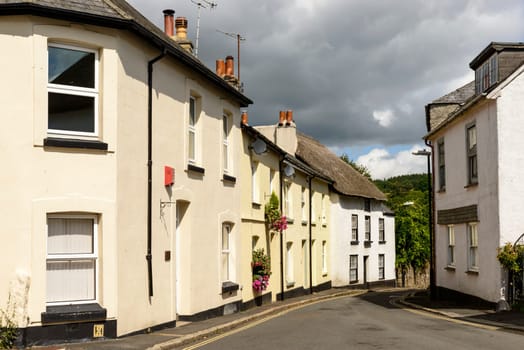 view of bending street with old houses in the touristic village in the Dartmoor region.