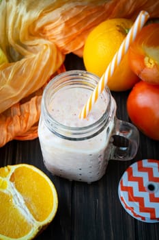 Healthy carrot, persimmon and orange smoothie in a jar with tube wooden background. Vertical image