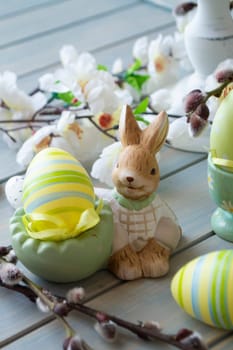 Beautiful Easter composition with eggs and rabbit decoration on wooden planks table