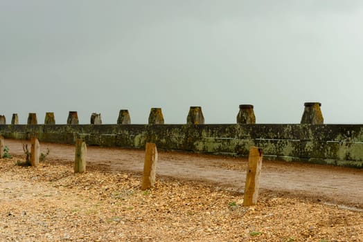 detail of foot path delimitattion at shingle beach of touristic location, shot under bright cloudy sky.
