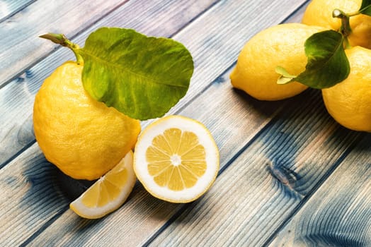 Closeup of ripe lemons with leaves on an old wooden table. Healthy nutrition. Health.