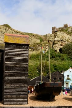 foreshortening of old fishing boat aground amid old net huts in historic village of Hastings, East Sussex .