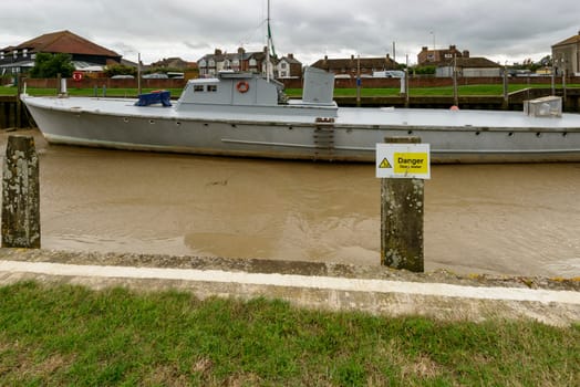 view of a large boat aground at low tide at embankment of river harbor at the historic village of Rye, East Sussex .