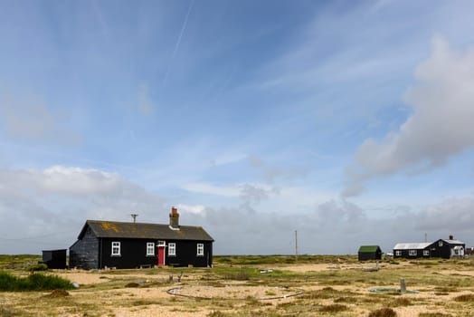 landscape of the marsh with holiday bungalow painted in black near the seaside at Dungedness,  Romney Marsh, Kent.