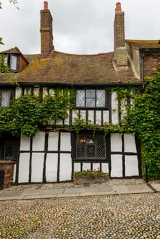 view of old wattle cottage covered with vine in small  historic village of Rye, East Sussex .