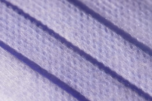 Super macro image showing the surface texture of a 3 ply single use face mask. Medical mask with 3 folds, splash proof and filtering ability.