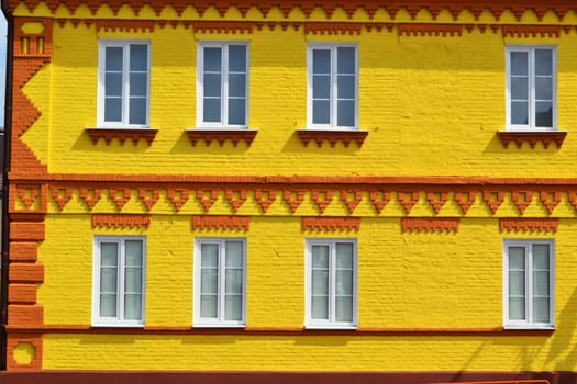 The facade of a house made of brick painted in yellow and windows, beautiful bright background