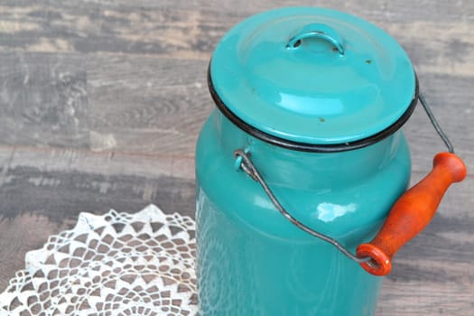 Old blue milk can onwooden background in vintage style close up
